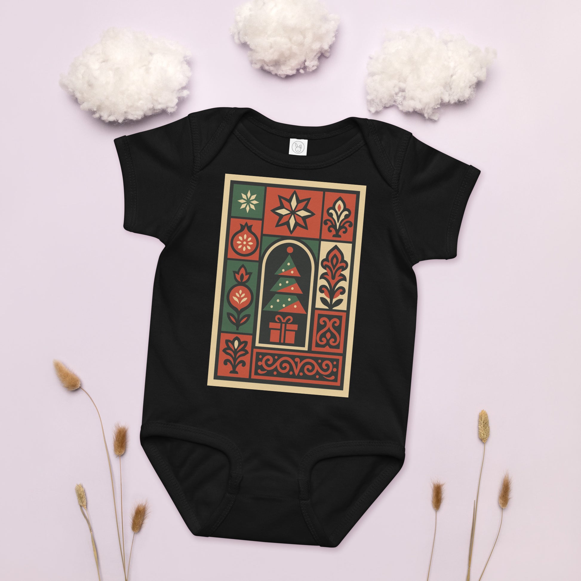 Black baby onesie with a festive design on a light pink background with decorative elements.