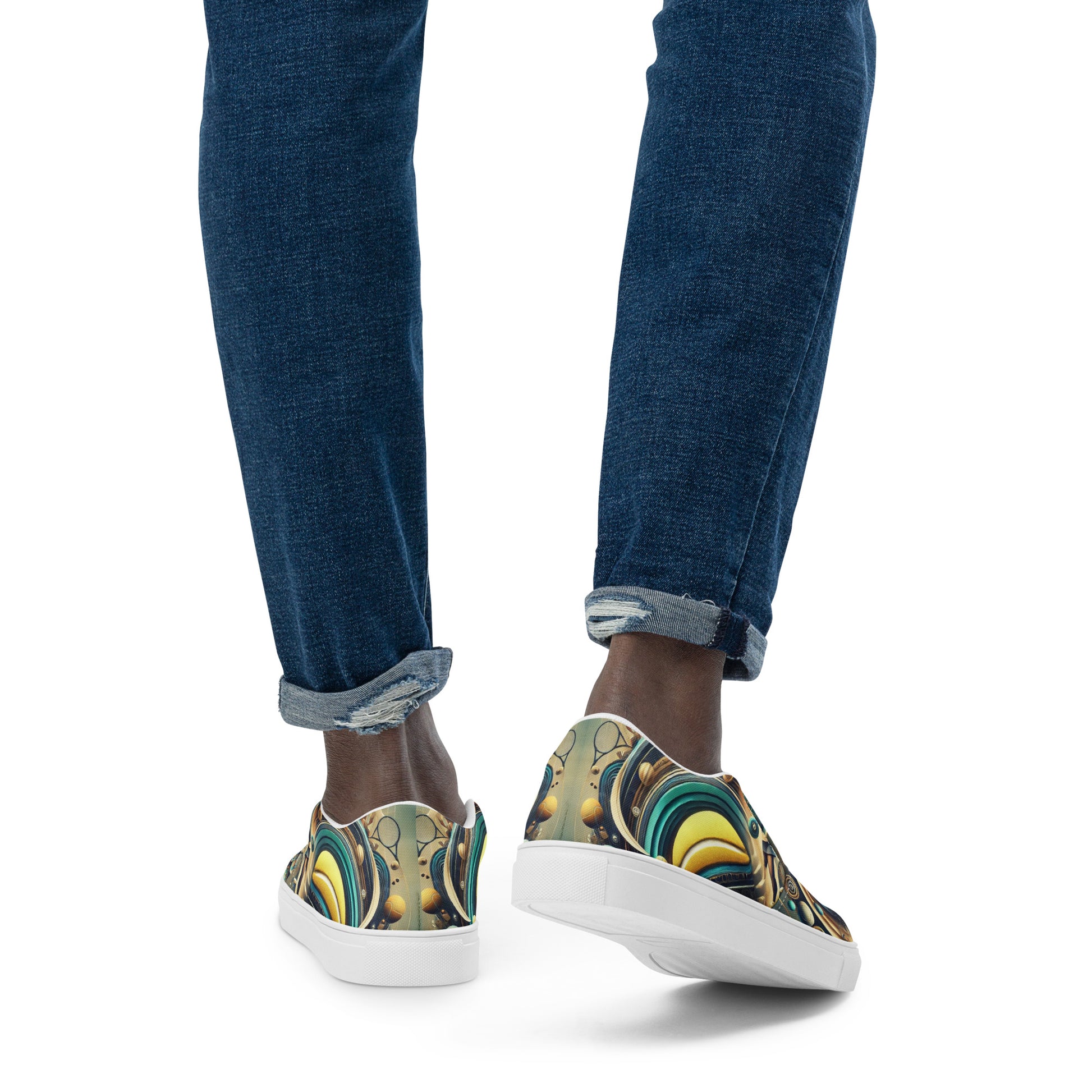 Colorful slip-on shoes with abstract design worn with blue jeans on a white background