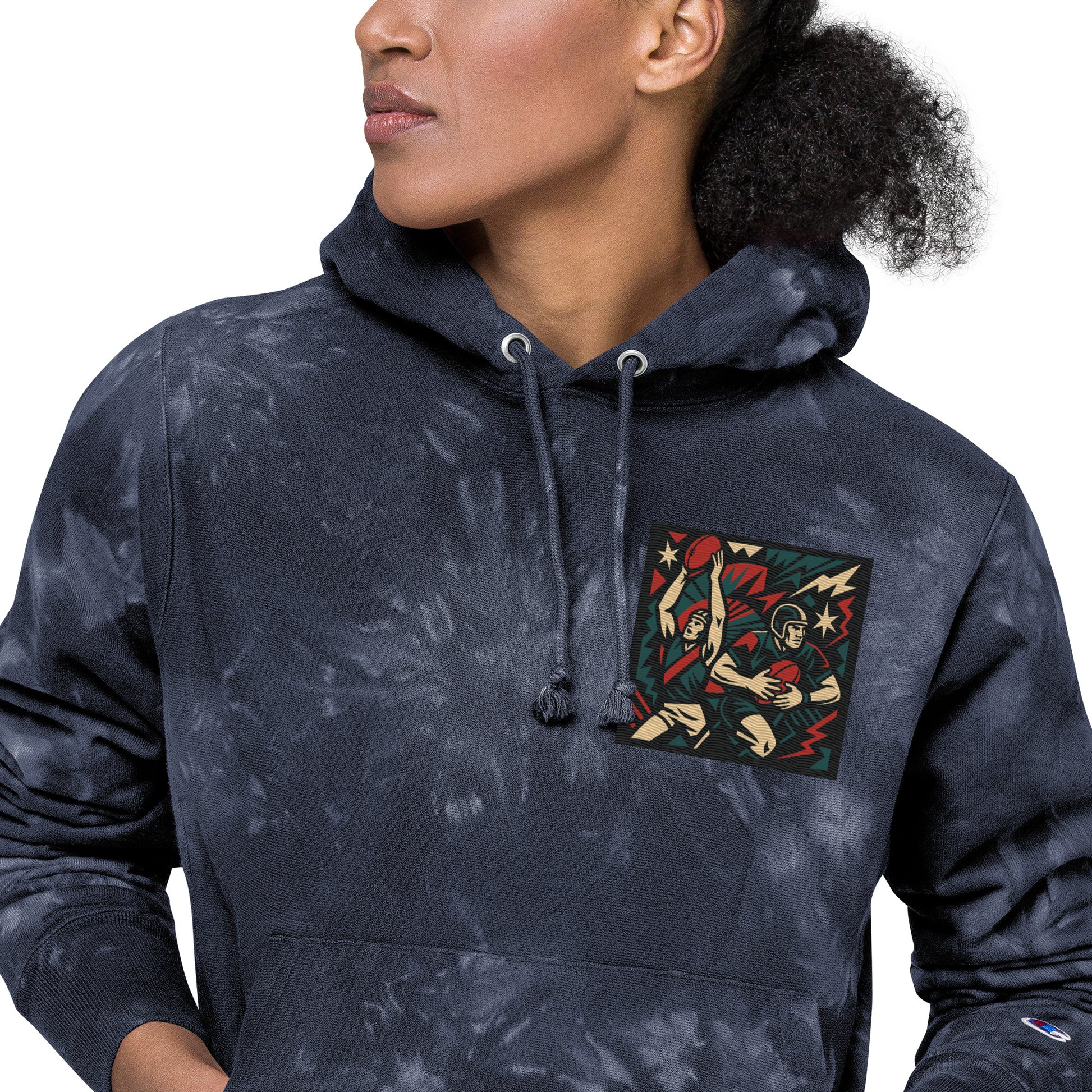 Person wearing a navy tie-dye hoodie with a colorful graphic on the chest pocket against a white background