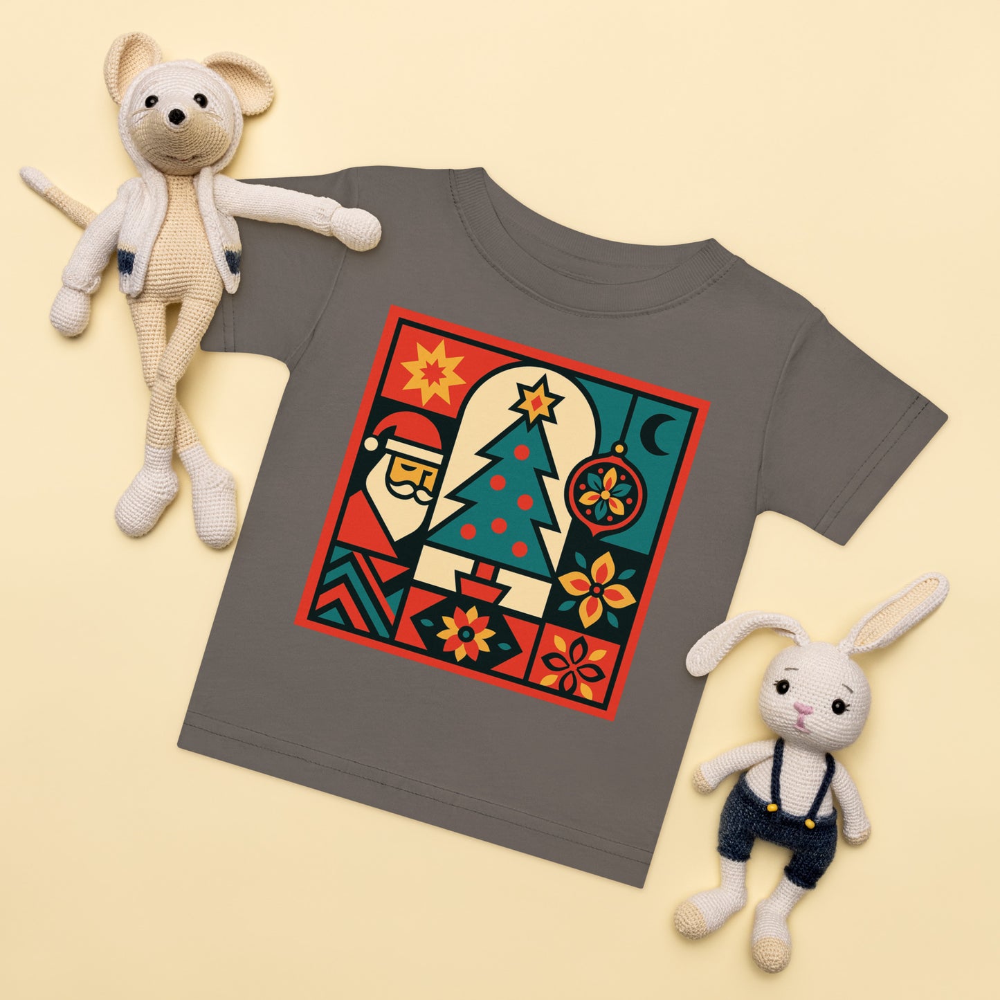 Gray t-shirt with a colorful graphic design, surrounded by two plush toys on a light yellow background